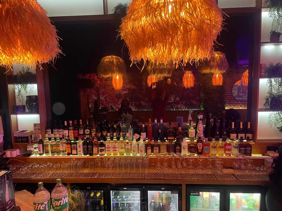 ESQ main bar with orange pendant lights and a wall of bottles